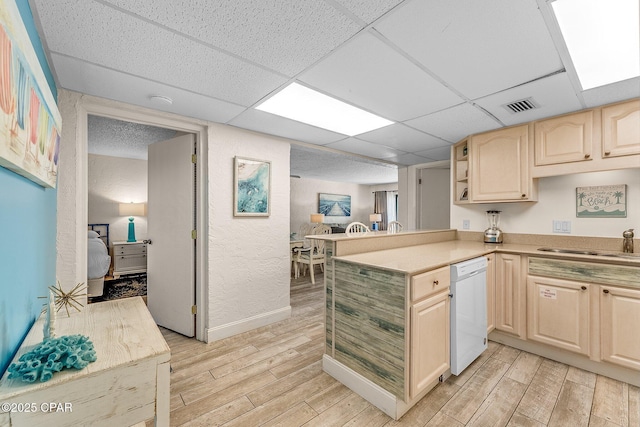 kitchen with dishwasher, light wood finished floors, a sink, and visible vents