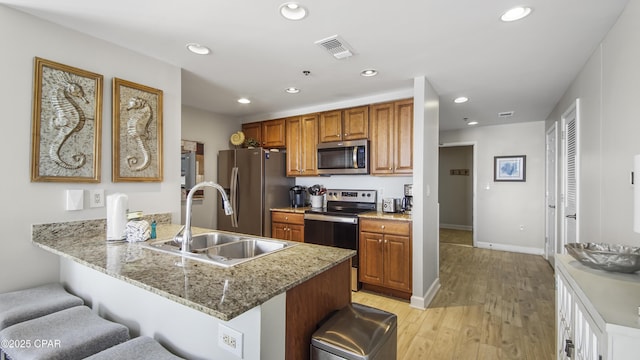 kitchen with a breakfast bar, recessed lighting, appliances with stainless steel finishes, a sink, and a peninsula