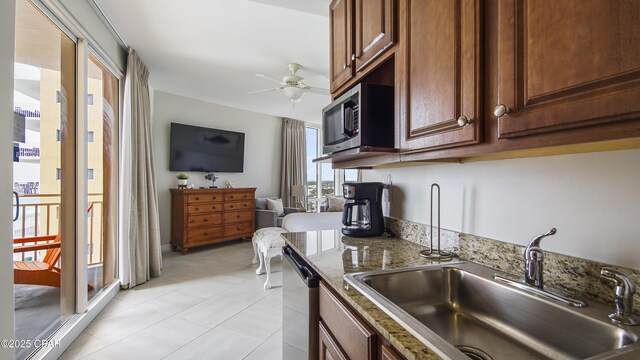 kitchen with ceiling fan, light stone counters, open floor plan, stainless steel appliances, and a sink