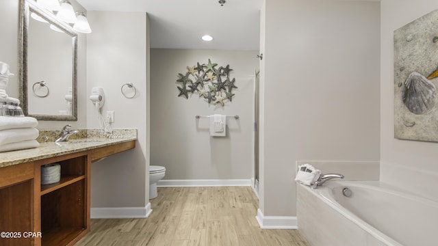 full bathroom with a garden tub, toilet, vanity, wood finished floors, and baseboards