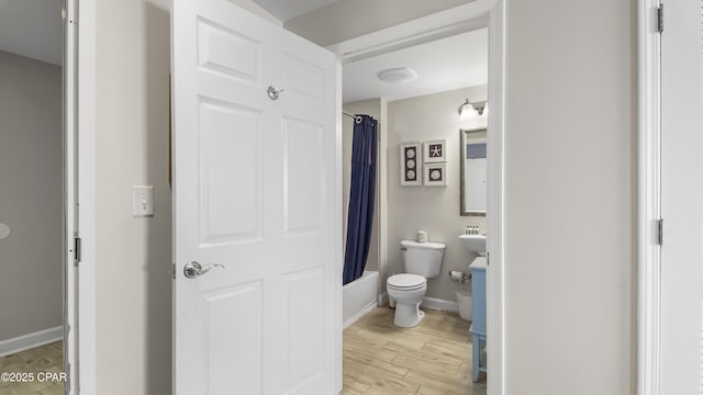 bathroom featuring shower / bath combo, baseboards, toilet, and wood finished floors