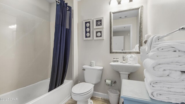 bathroom featuring toilet, shower / tub combo, wood finished floors, visible vents, and baseboards