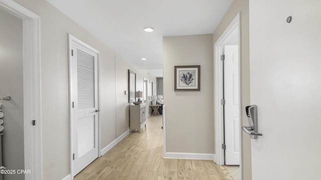 hallway with light wood-type flooring and baseboards