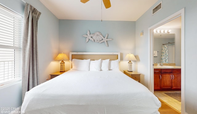 bedroom featuring ensuite bath, visible vents, ceiling fan, and a sink