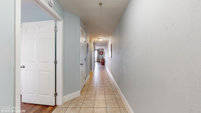 hall with light tile patterned floors and baseboards