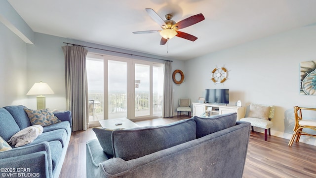 living area with baseboards, a ceiling fan, and wood finished floors