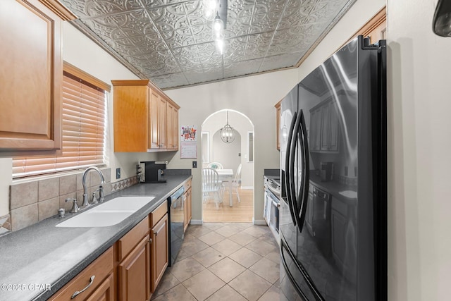 kitchen with an ornate ceiling, arched walkways, freestanding refrigerator, a sink, and dishwasher