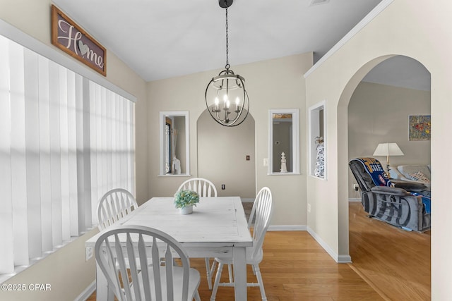 dining room featuring light wood-type flooring, a notable chandelier, and baseboards