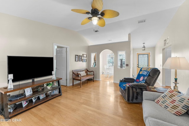 living room featuring light wood-style floors, arched walkways, visible vents, and lofted ceiling