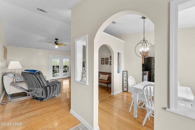 corridor with light wood-style floors, baseboards, visible vents, and a chandelier