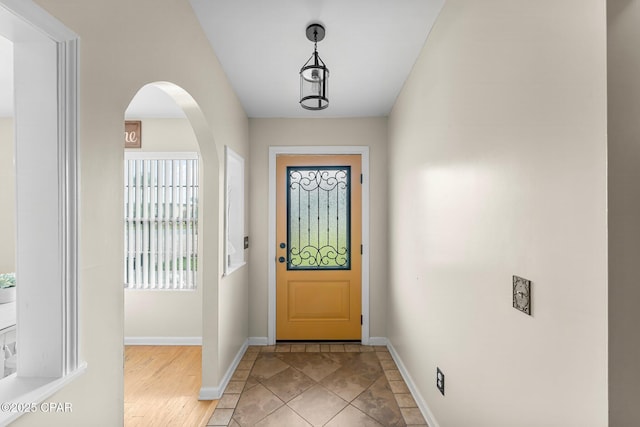 foyer entrance with baseboards, arched walkways, and light tile patterned flooring