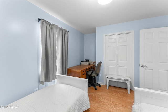 bedroom with light wood-style flooring, baseboards, and a closet