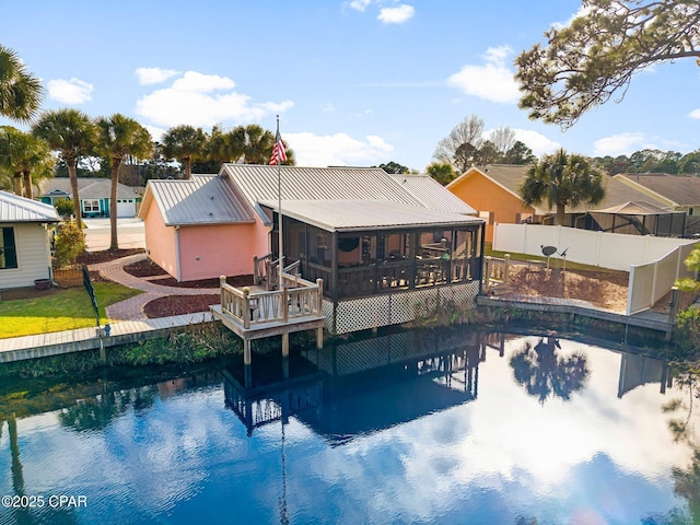 rear view of property featuring a sunroom, metal roof, and fence