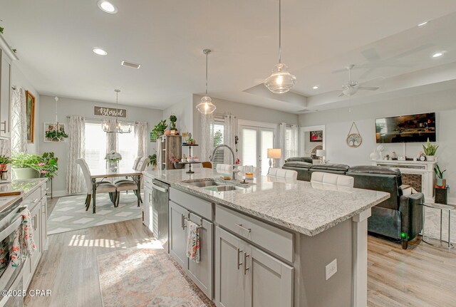 kitchen featuring an island with sink, stainless steel appliances, light wood-style floors, a sink, and recessed lighting