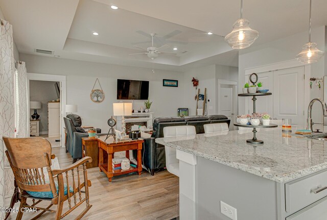 kitchen with light wood-type flooring, a tray ceiling, visible vents, and recessed lighting