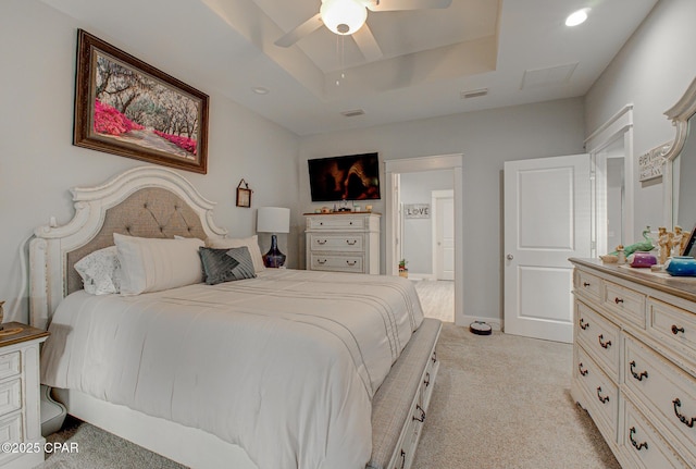 bedroom featuring ceiling fan, light colored carpet, visible vents, baseboards, and a tray ceiling