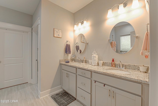 full bath featuring double vanity, a sink, and baseboards