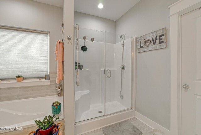 full bathroom featuring a stall shower, a bath, and baseboards