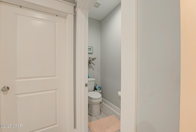 bathroom featuring toilet, baseboards, visible vents, and wood finished floors