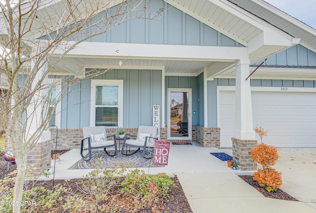 entrance to property featuring a garage, a porch, board and batten siding, and brick siding