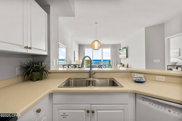 kitchen featuring light countertops, dishwasher, white cabinets, and a sink