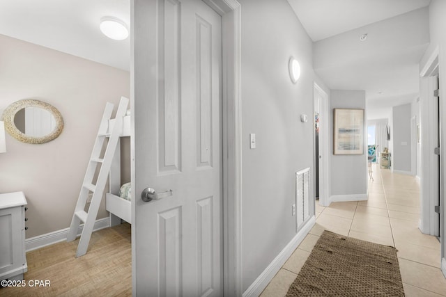 hall featuring baseboards, visible vents, and light tile patterned floors