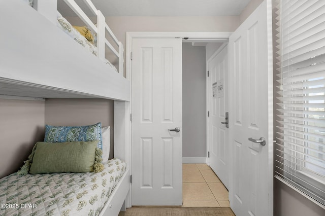 bedroom with light tile patterned floors, a closet, and baseboards