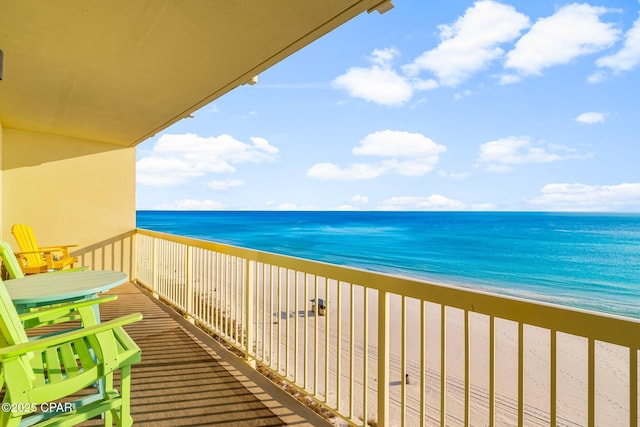 balcony with a water view and a view of the beach