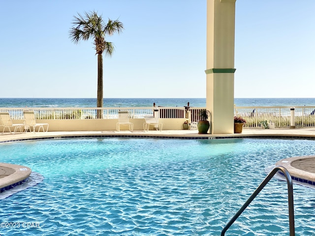 community pool with fence and a water view