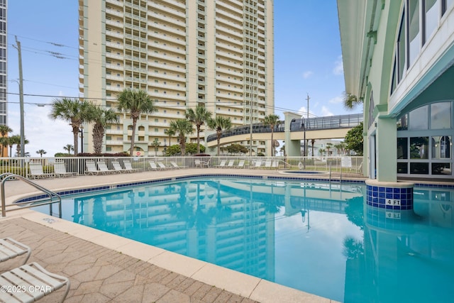 community pool featuring fence and a hot tub