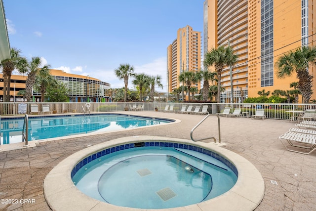 pool featuring fence, a community hot tub, and a patio