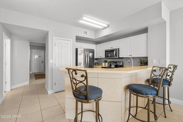 kitchen with light tile patterned flooring, visible vents, a peninsula, and stainless steel appliances