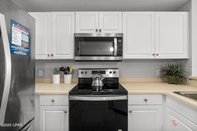kitchen with appliances with stainless steel finishes, white cabinetry, light countertops, and tile patterned flooring