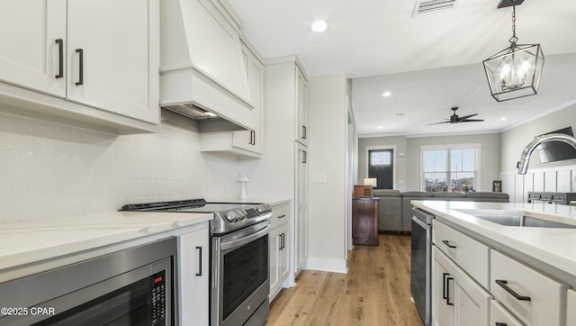 kitchen featuring stainless steel appliances, a sink, visible vents, white cabinets, and custom range hood