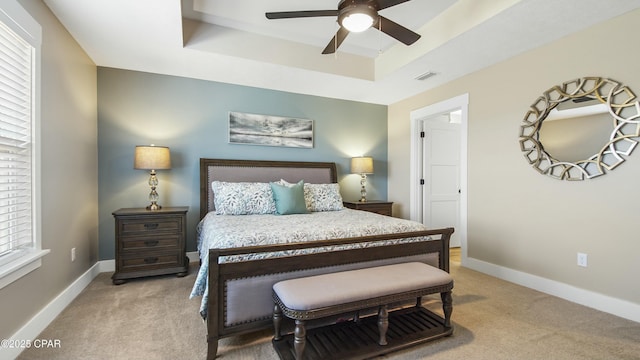 bedroom featuring a raised ceiling, light colored carpet, and baseboards