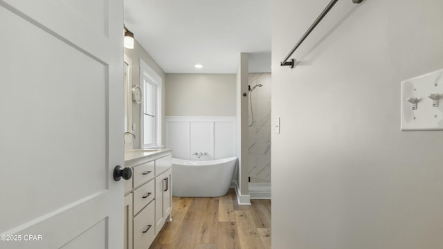 full bath with a soaking tub, a stall shower, wainscoting, vanity, and wood finished floors