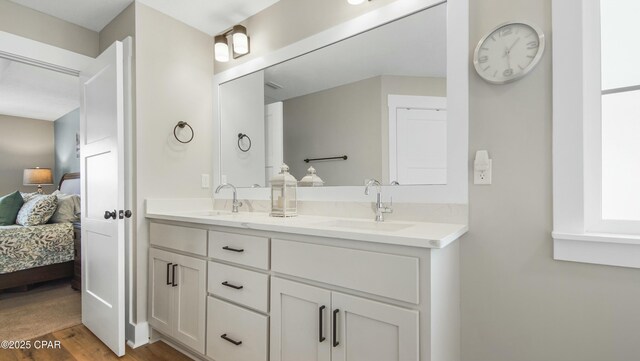 ensuite bathroom with double vanity, wood finished floors, a sink, and ensuite bathroom