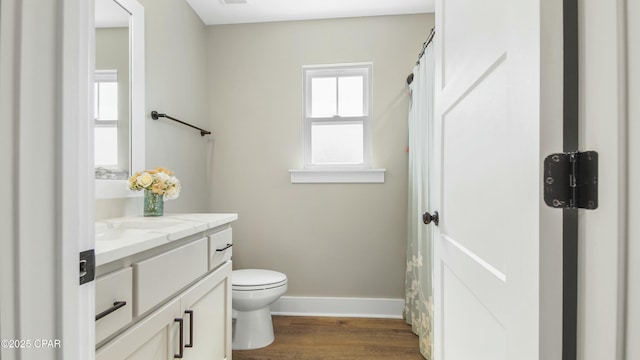 full bath featuring toilet, wood finished floors, vanity, and baseboards