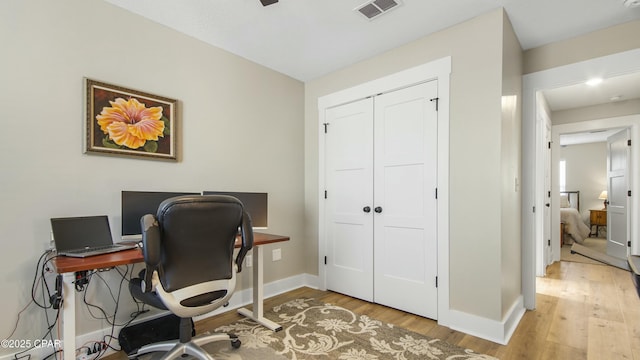 home office featuring light wood finished floors, visible vents, and baseboards