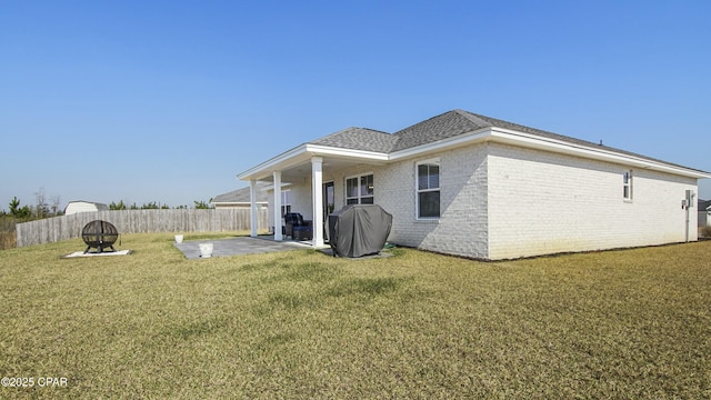 back of property with a patio area, brick siding, fence, and a lawn