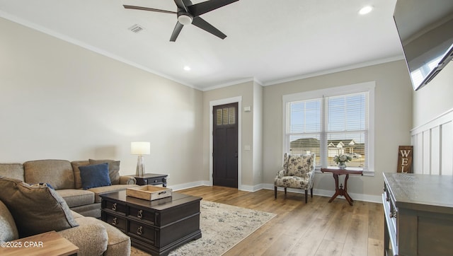 living room featuring baseboards, ornamental molding, visible vents, and light wood-style floors