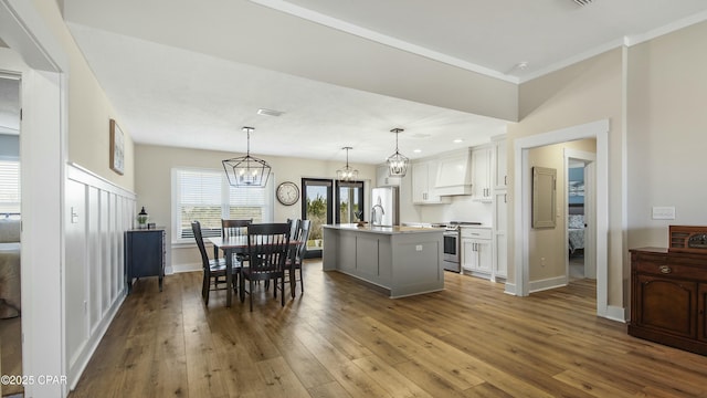 kitchen with custom exhaust hood, a kitchen island with sink, appliances with stainless steel finishes, and dark wood finished floors