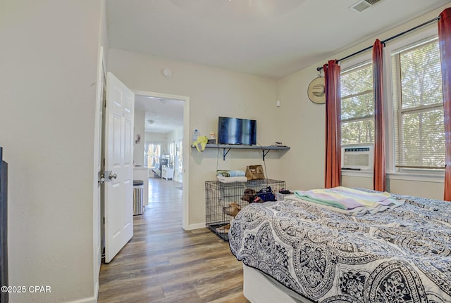 bedroom with baseboards, visible vents, cooling unit, and wood finished floors