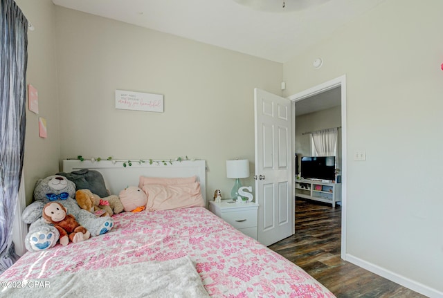 bedroom with baseboards and dark wood-type flooring