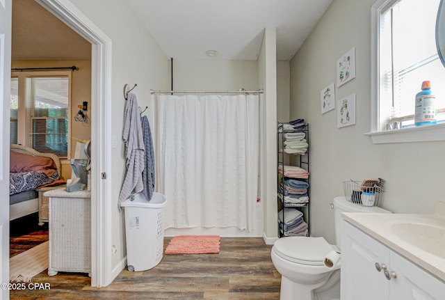 ensuite bathroom featuring a shower with shower curtain, a healthy amount of sunlight, wood finished floors, and ensuite bathroom