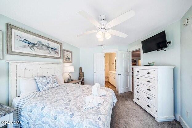 carpeted bedroom featuring ensuite bath, a ceiling fan, and baseboards