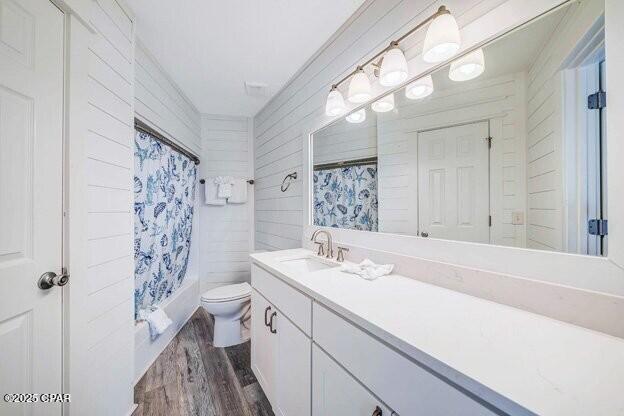 bathroom with shower / tub combo, vanity, toilet, and wood finished floors