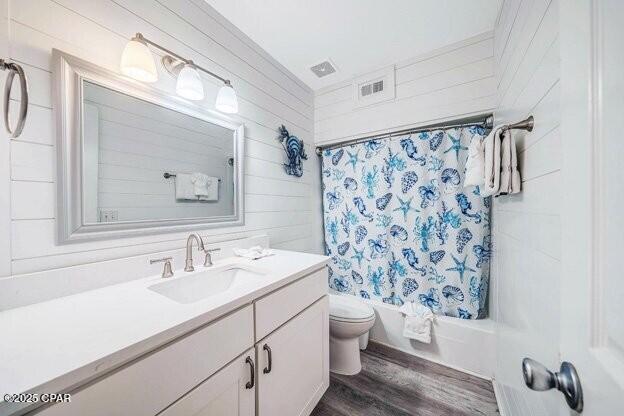 full bath with visible vents, shower / bathtub combination with curtain, toilet, vanity, and wood finished floors