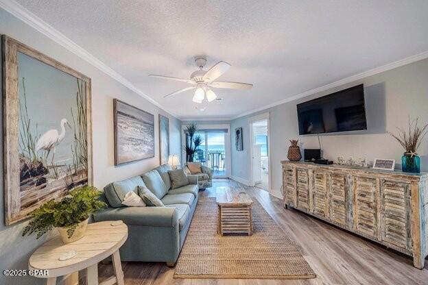 living area with crown molding, a textured ceiling, and wood finished floors