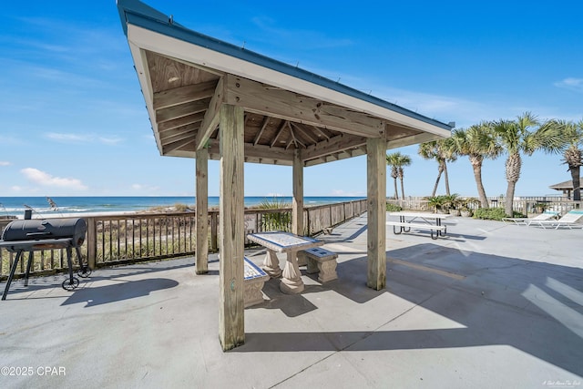 view of patio with a view of the beach, a water view, a grill, and a gazebo